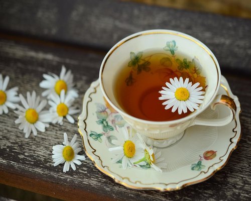 A cup of herbal tea next to a notebook on a wooden table